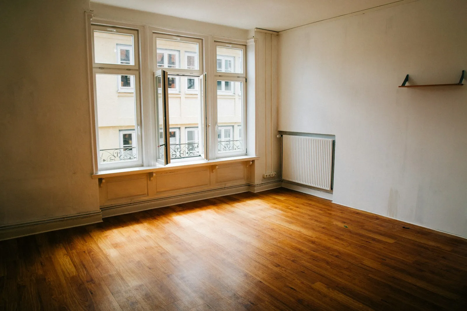 Stanza completamente vuota con pavimento in legno e grande finestra